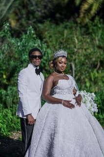 Bride and groom in a white tuxedo and ball gown in a garden, photographed by Picha Media