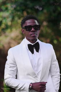 Groom in a white tuxedo and black bow tie, photographed by Picha Media
